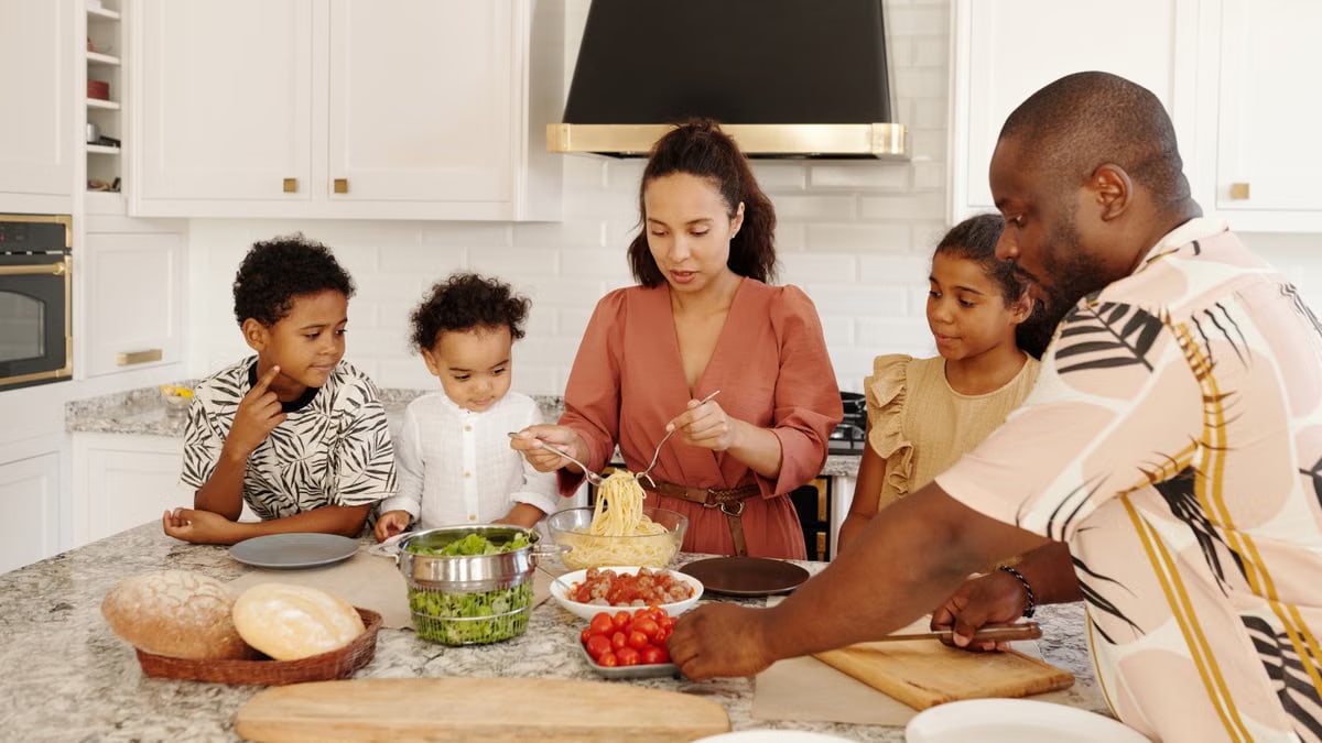 A diverse family prepares pasta in a modern white kitchen, conveying unity and culinary art.